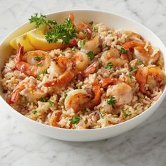 shrimp and rice with lemon wedges in a white bowl on a marble countertop