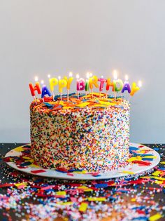 a birthday cake with lit candles and sprinkles