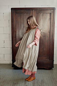 Victorian style inspired pinafore dress with flutter sleeve made from 100% soft and washed Oeko-Tex certified linen Details: - Composition: 100% Oeko-Tex certified linen - Colour: Natural - Coconut buttons down the back - Size: XS-S, M, L-XL - Medium weight linen - Linen care: machine wash gentle; tumble dry low, ironing optional - The price is for one pinafore dress, other pictured items are not included Dress With Wings, Pretty Apron, Dress With Flutter Sleeves, Dress Linen, Womens Aprons, Apron Dress, Prairie Dress, Pinafore Dress, French Linen