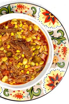 a white bowl filled with food on top of a colorful plate