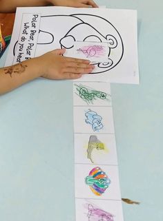 a child's hand holding up a piece of paper with drawings on it