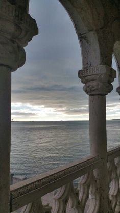 an archway overlooking the ocean on a cloudy day