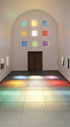 an empty room with several colored squares on the floor and one door in the center