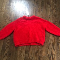 a red sweater laying on top of a wooden floor