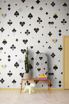 a room with a table, potted plant and playing cards wallpaper