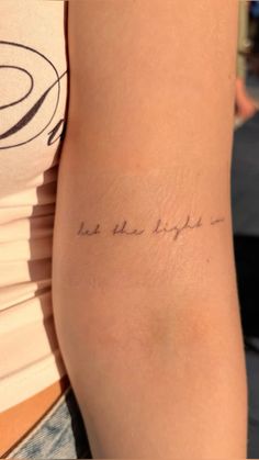 a woman with a tattoo on her arm that says be the light