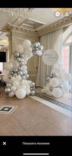 a large balloon arch in the middle of a room filled with white and silver balloons