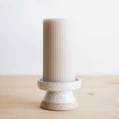 a white vase sitting on top of a wooden table