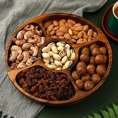 nuts and other foods are arranged in a wooden bowl on a table next to a cup of coffee