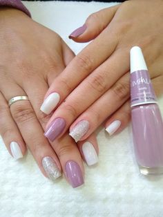 two hands with white and pink manies holding each other's nails, one has a ring on it