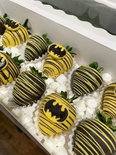 chocolate covered strawberries with yellow and black stripes are arranged in a box on display