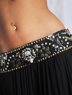 a close up of a woman's belly wearing a black dress and gold jewelry