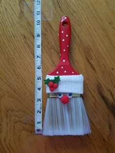 a red and white brush sitting on top of a wooden table next to a ruler