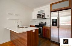 an empty kitchen with stainless steel appliances and wood flooring is pictured in this image