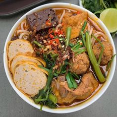 a bowl filled with noodles, meat and veggies on top of a table