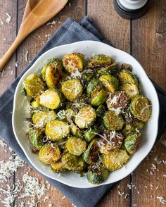 a white bowl filled with brussel sprouts covered in parmesan cheese