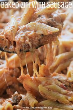 a spoon full of baked ziti with sausage and pasta is being lifted from a casserole dish