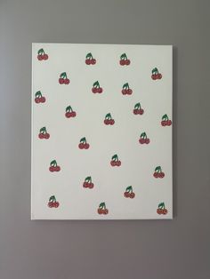 a piece of paper with cherries on it sitting on top of a white wall