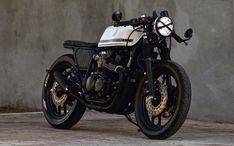 a white and black motorcycle parked next to a wall