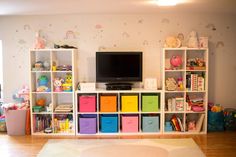 a living room filled with lots of toys and bookshelves next to a flat screen tv