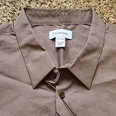 For An Additional 30 Percent Off, Just Bundle 3+ Items! Free Shipping With Orders Over $50! Calvin Klein Makes A Beautiful Line Of Dress Shirts. This Long-Sleeve Stretch Cotton Brown Shirt Is Another Hit! The Brown Color Is Called "Falcon." There Is A 'Ck' Logo On The Left Chest. Made Of 76 Percent Cotton, 21 Percent Polyamide And 3 Percent Elastane. Comes With A Extra Buttons. Made In Indonesia. Shipped From Minnesota! Calvin Klein Casual Short Sleeve Shirt, Casual Calvin Klein Short Sleeve Shirt, Calvin Klein Casual Relaxed Fit Shirt, Casual Collared Tops By Calvin Klein, Calvin Klein Casual Collared Top, Casual Calvin Klein Collared Top, Calvin Klein Short Sleeve Shirt For Spring, Calvin Klein Cotton Summer Shirt, Calvin Klein Solid Tops For Summer