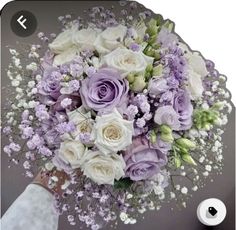 a bridal bouquet with white and purple flowers is shown in this image, the bride's hand holds it