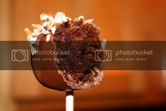 a chocolate dessert on top of a spoon with marshmallows and other toppings