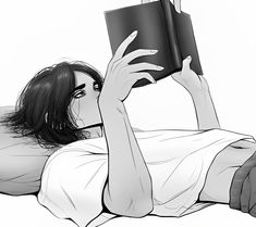 a woman laying on the floor reading a book with her hands up to her face