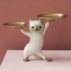 a cat figurine holding two gold plates on it's back and arms