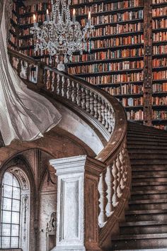 a staircase with bookshelves and chandelier in the background