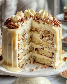 there is a large cake with white frosting and pecans on the top layer