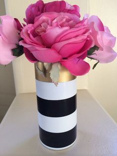 a black and white striped vase with pink flowers