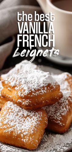 three powdered sugar covered doughnuts on a plate next to a cup of coffee