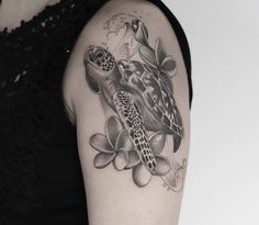 a woman's arm with a turtle and flowers tattoo on it