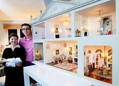 a man and woman standing in front of a doll house that is built into the floor