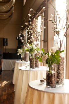 vases filled with flowers and rocks are lined up on a table in front of a window