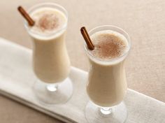 two glasses filled with drinks sitting on top of a table