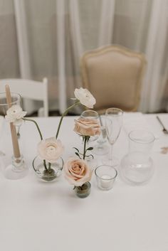 there are many vases with flowers in them on the white table cloth at this wedding reception