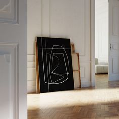 a black and white painting sitting on top of a hard wood floor next to a doorway