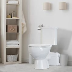 a white toilet sitting in a bathroom next to a shelf filled with towels and other items