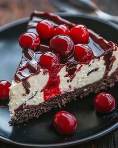 a piece of cheesecake with cherries on top is sitting on a black plate