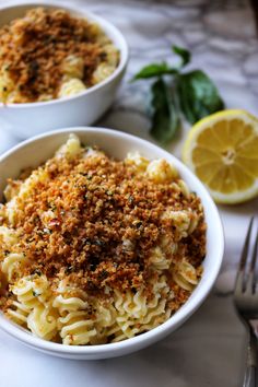 two white bowls filled with pasta and garnished with parmesan sprinkles