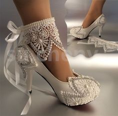 a pair of white high heeled shoes with lace and pearls