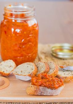 bread with tomato sauce on it sitting on a cutting board next to a jar of jam