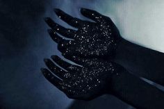 two black hands with glitter on them in the dark