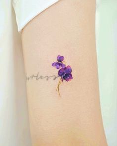 a small purple flower tattoo on the side of a woman's leg that reads, whatever