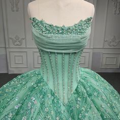 Experience a dream come true with this luxurious mint green Quinceanera ball gown. The corset style beaded bodice is reminiscent of an old west saloon, with intricate bead work adorning the top. A princess V waist and heavily beaded, sequined full skirt create an exquisite silhouette. Complete with a train and ribbon tie lace up back, for a customizable fit. material: organza color: as shown type: party ball gown fitted bodice built in bra scalloped neckline lace up back court train shown as size 2 Emerald Green Xv Dresses, Green Quinceanera Dress, Quinceanera Dances, Gown Fitted, Green Quinceanera, Green Quinceanera Dresses, Beaded Ball Gown, Quinceanera Themes Dresses, Princesa Tiana