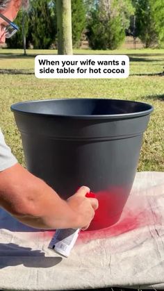 a man is painting a large black pot with red paint on the outside and inside