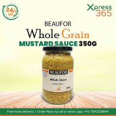 a jar of mustard sitting on top of a wooden table next to a sign that reads beaufor whole grain mustard sauce 350g