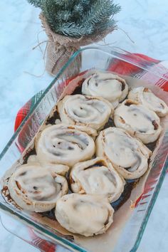 a glass dish filled with cinnamon rolls on top of a table